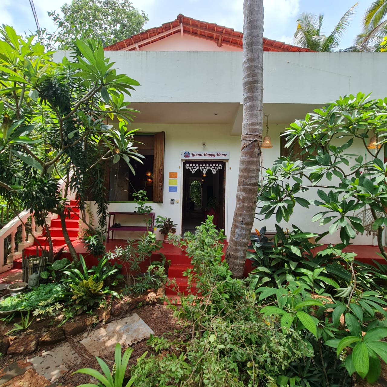 The entrance and leafy garden of Laxmi Happy Home in Querim, Goa