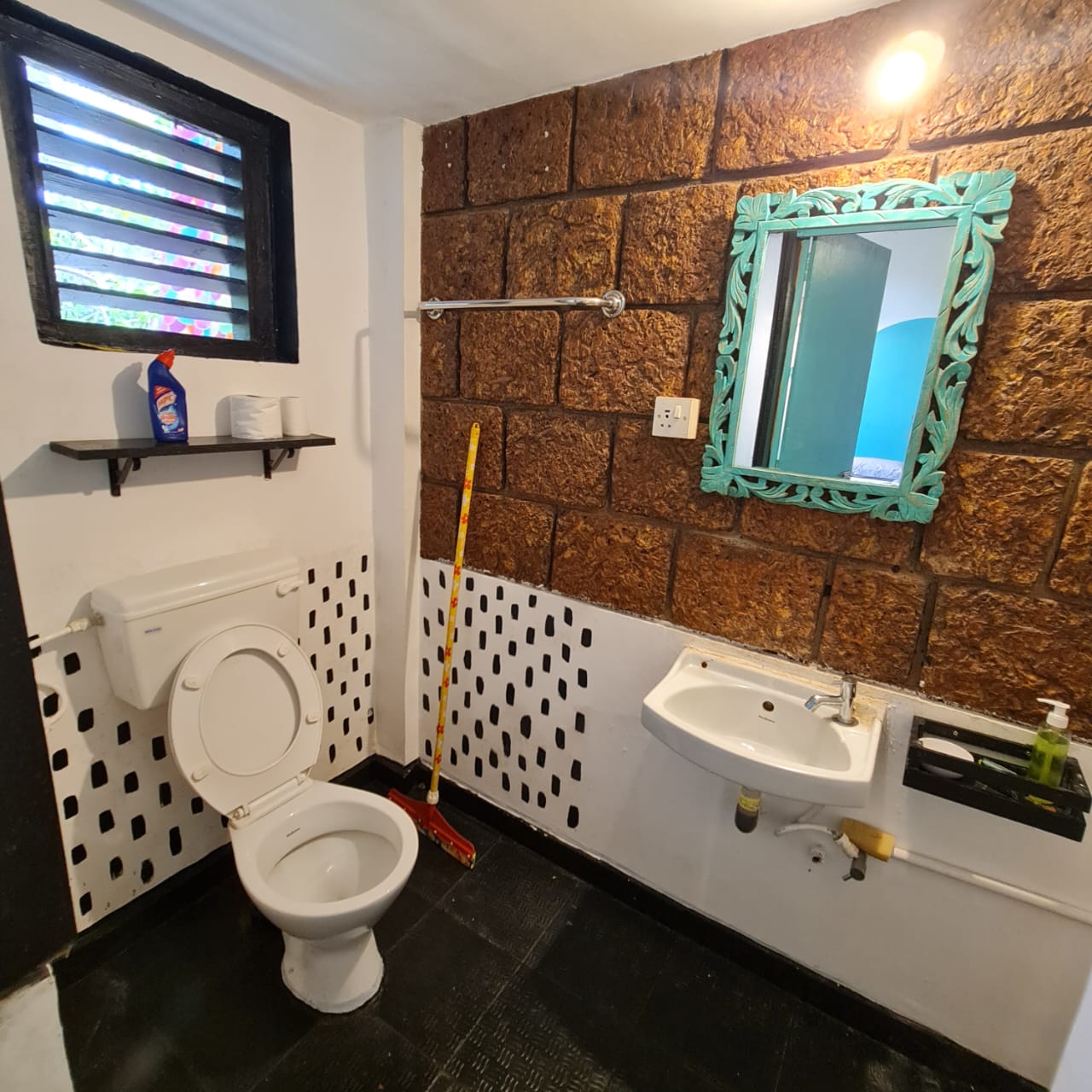 Jala attached bathroom with toilet, basin and turquoise-framed mirror