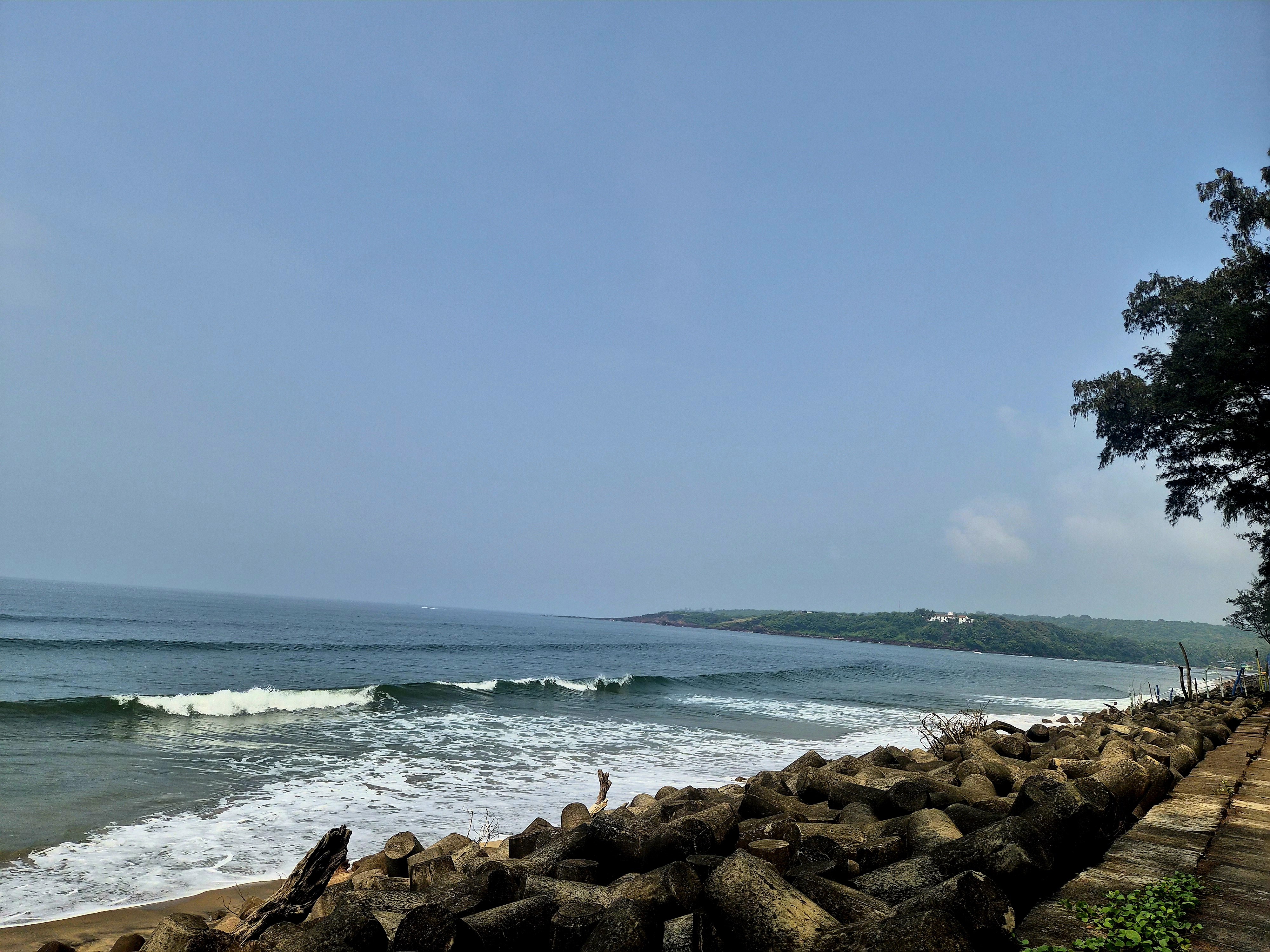 Waves, coastal stones and a green headland across the water