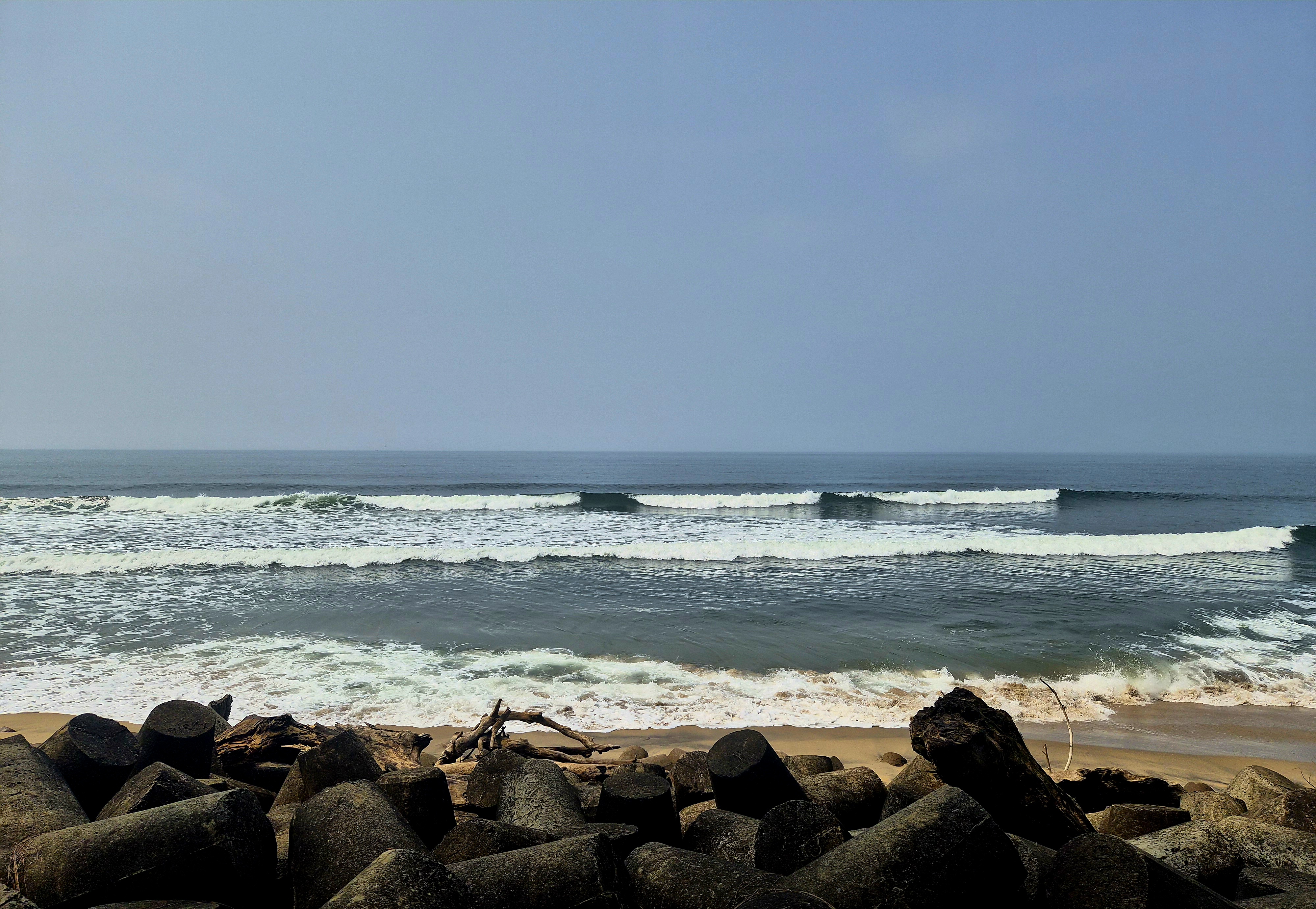 Ocean waves rolling toward the sandy shore and coastal stones