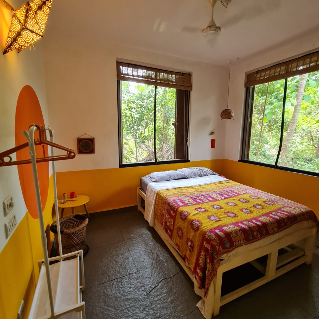 Agni room with orange and yellow walls, a double bed and two garden-facing windows