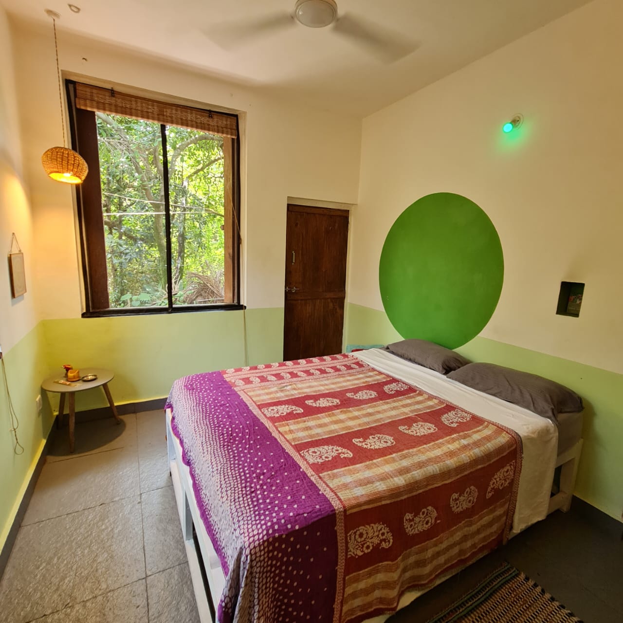 Vayu room at Laxmi Happy Home, with its green circular wall feature, double bed and garden-facing window